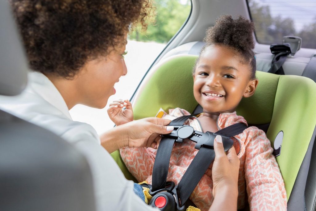 Mom secures daughter in car seat