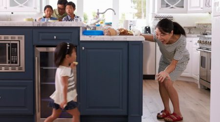 A mother playing with her daughter in a kitchen.