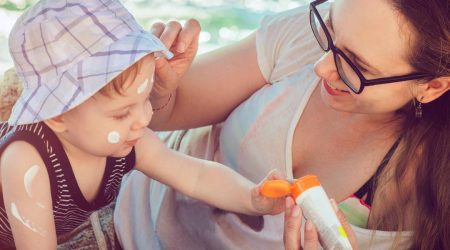 Mom applies sunscreen to child before going to beach