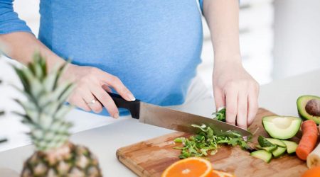 Pregnant woman cutting healthy food.