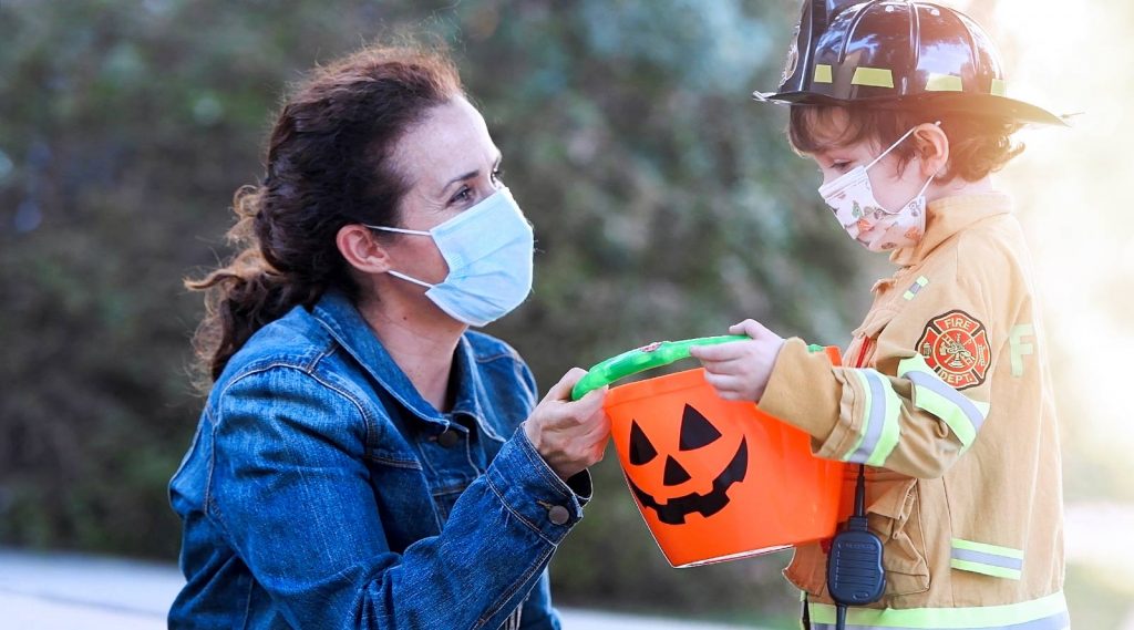 A mother and a child dressed as a fireman. Both are wearing masks due to COVID-19.