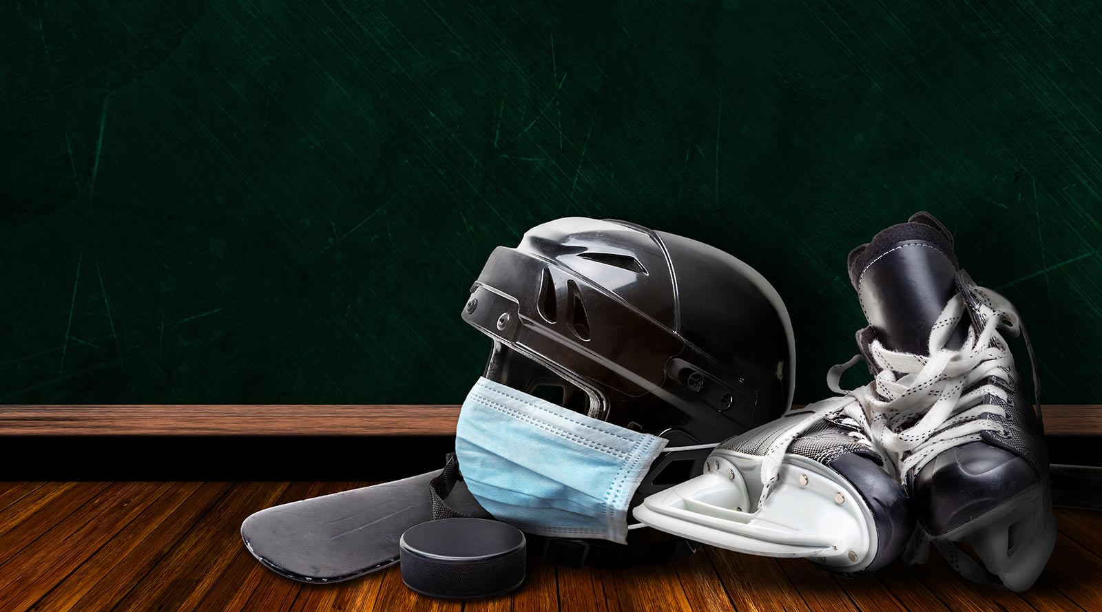 Hockey gear on a floor with a mask over the helmet.
