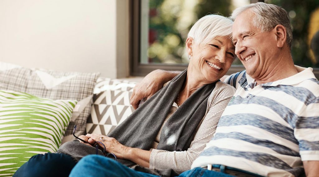 An elderly couple sitting together on a couch.