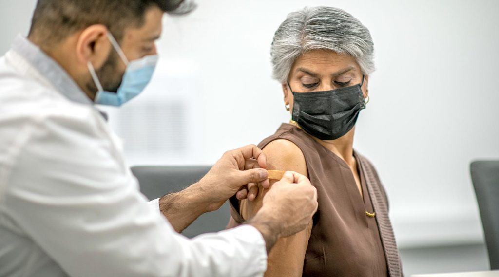 A doctor applies a bandage to an elderly woman's arm.