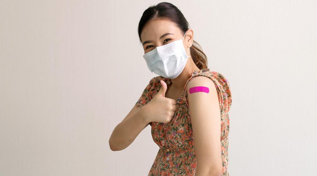 A teenager gives a thumbs up after receiving a COVID-19 vaccination.