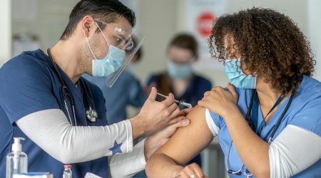 A nurse receives a COVID-19 vaccination.