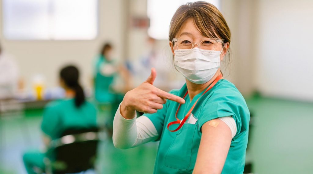 A nurse points to her arm where she received the COVID-19 vaccine.