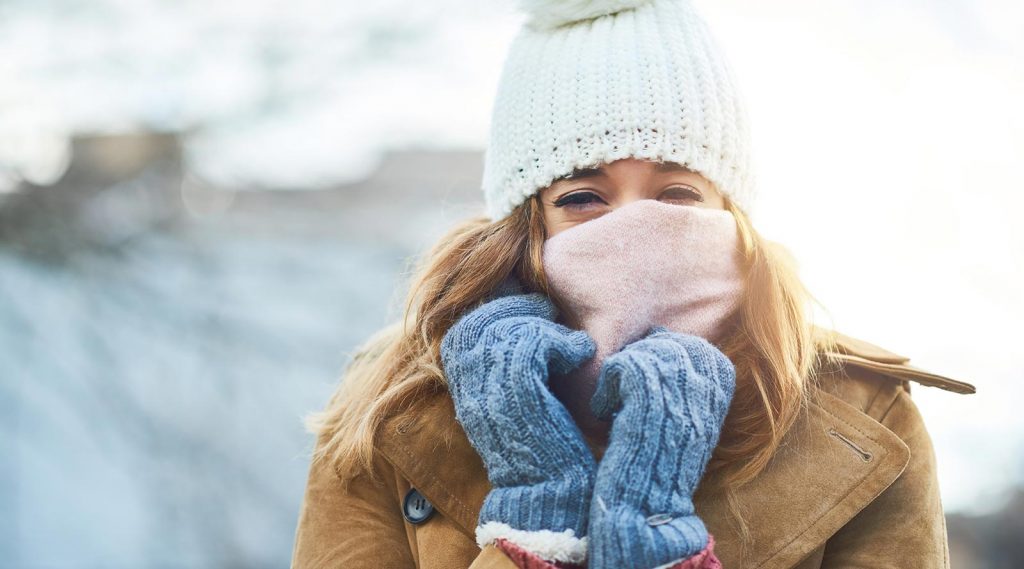 Woman in cold weather wearing a hat, gloves and a scarf.