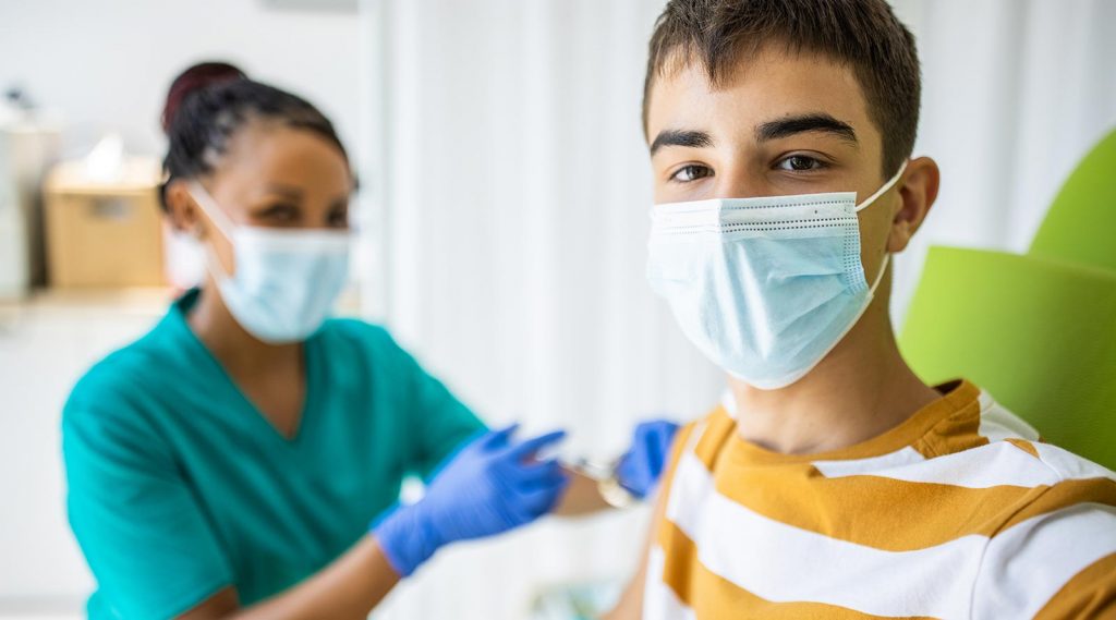 A teenager taking a selfie while getting the COVID-19 vaccine.