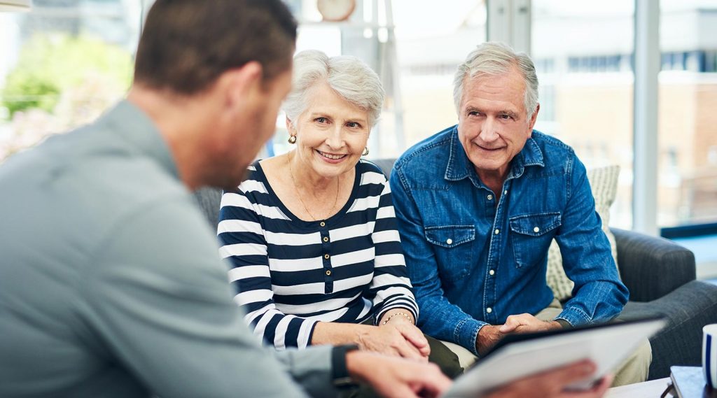 Someone helping an elderly couple with paperwork.