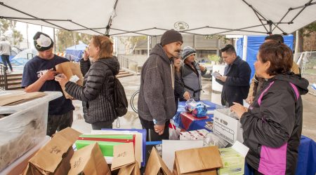Aimee Dunkle, left, and Suzanne Larkin, right, distribute Naloxone kits in paper bags to homeless people in Civic Center Plaza, Santa Ana, CA.