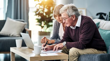 Cropped shot of a senior couple going over the household budget while sitting on their living room sofa at home.