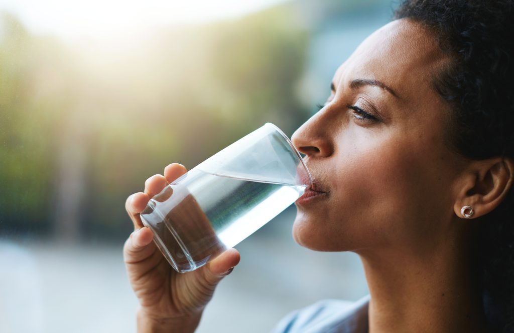 Shot of a woman drinking a glass of water at home.