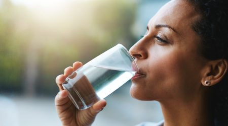 Shot of a woman drinking a glass of water at home.