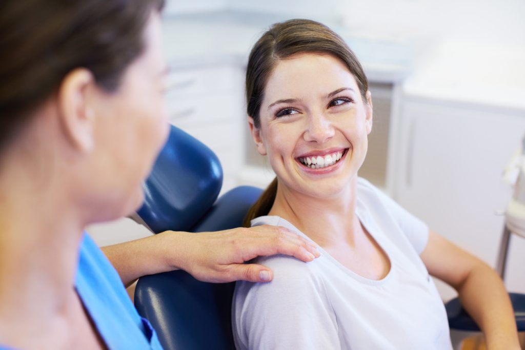 A pretty young woman having a conversation with her friendly dentist.