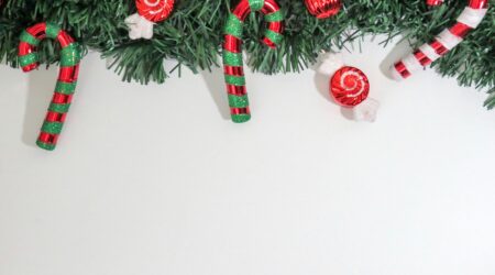 Christmas-themed image with candy canes and ornaments on greenery, perfect for holiday decorations.