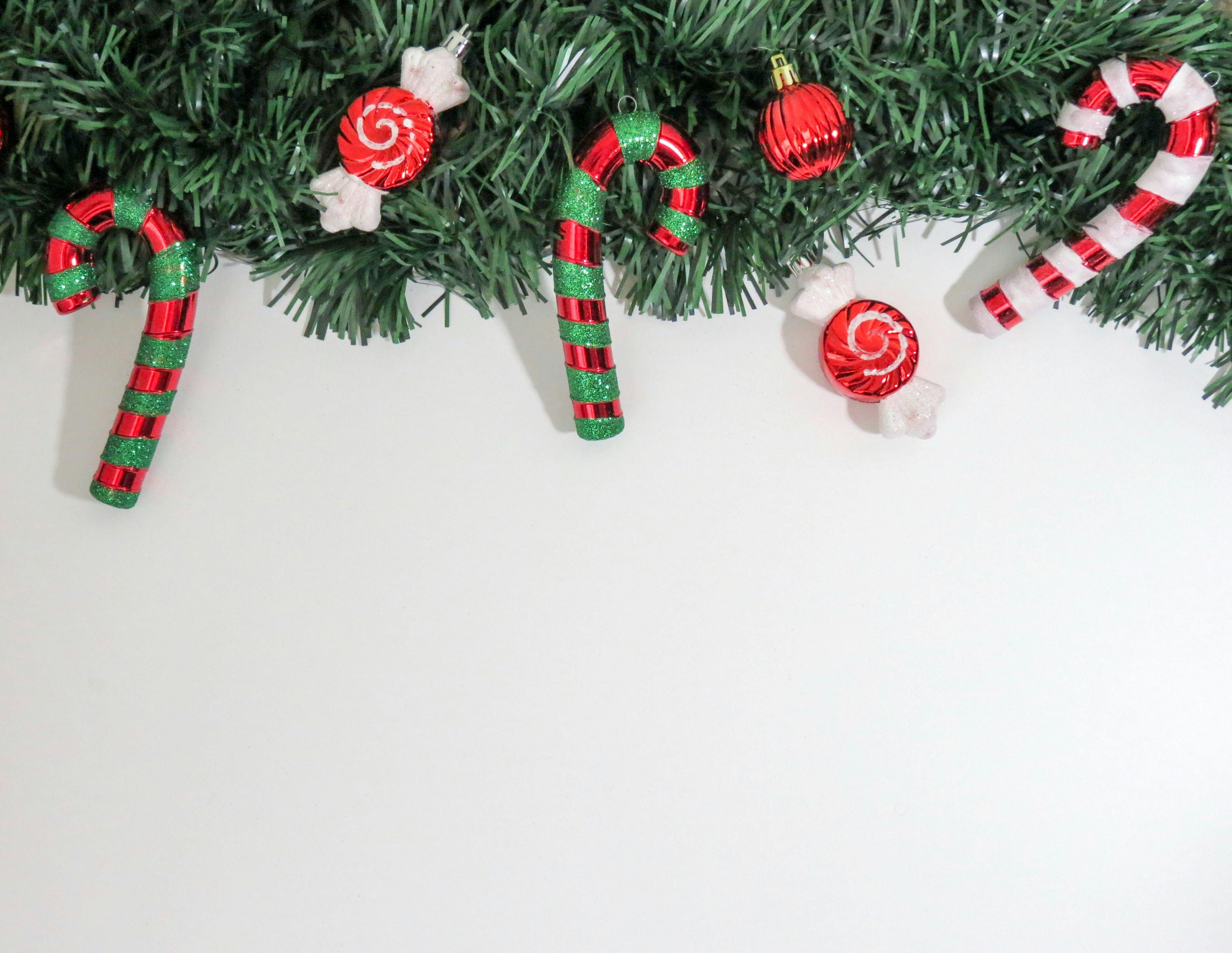 Christmas-themed image with candy canes and ornaments on greenery, perfect for holiday decorations.